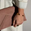Vrouw heeft vuilroze gestreepte Billie E. enveloppetas in de hand.