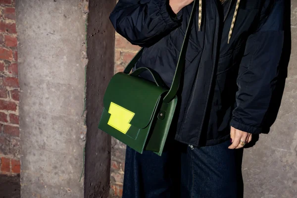 De groene Sofie L. met fluogeel contrast aan de schouder van een model.