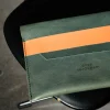 De Kate W. tablethoes in petrol leder met oranje sluitriem.